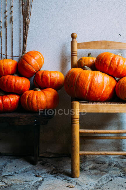 Блискучі апельсинові гарбузи складені на стільцях — стокове фото