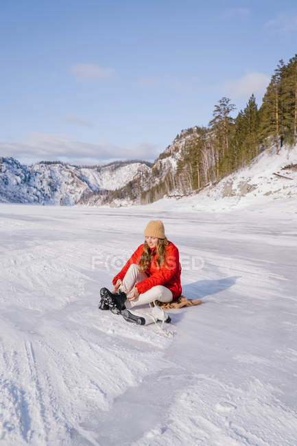 Woman sitting on snow and changing boots — Stock Photo