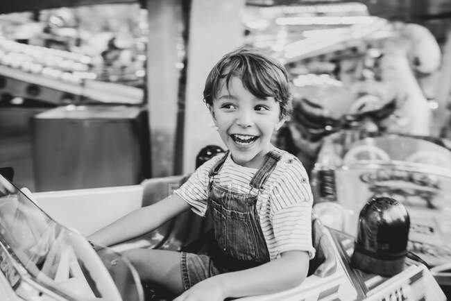 Niño feliz montar carrusel en el recinto ferial - foto de stock