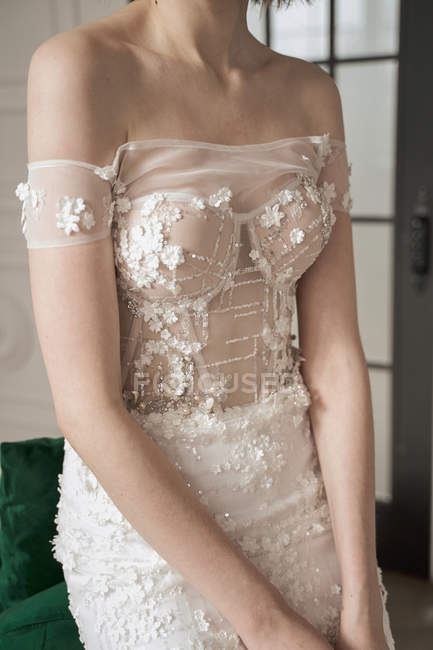Image recadrée de jeune mariée coûteuse en robe de dentelle blanche regardant loin et réfléchissant — Photo de stock