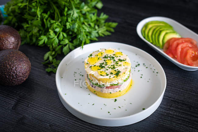 Von oben schmackhafte appetitliche Lima Ursache von Thunfisch mit grünen und in Scheiben geschnittenen Tomaten Avocado in weißen Tellern auf dem Tisch dekoriert — Stockfoto