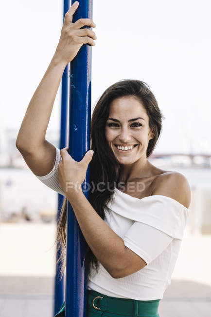 Bella sorridente giovane donna appesa su un palo in strada mentre guardava la fotocamera — Foto stock