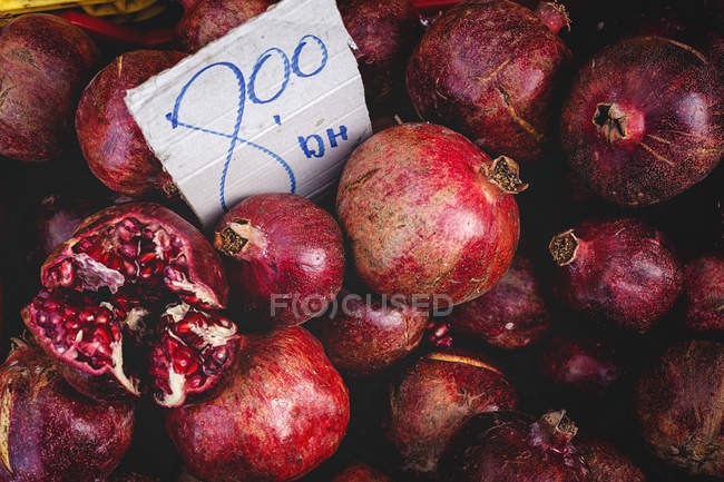 Stand full of ripe organic pomegranates with price tag at farmers outdoor market — Stock Photo