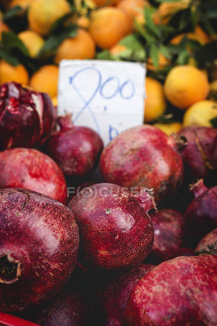 Стенд полный спелых органических гранатов и апельсинов с ценником на открытом рынке — стоковое фото