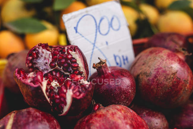 Stand lleno de granadas orgánicas maduras con etiqueta de precio en el mercado de agricultores al aire libre - foto de stock