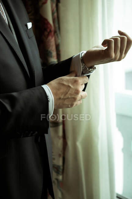 Человек застегивает рукав рубашки — стоковое фото