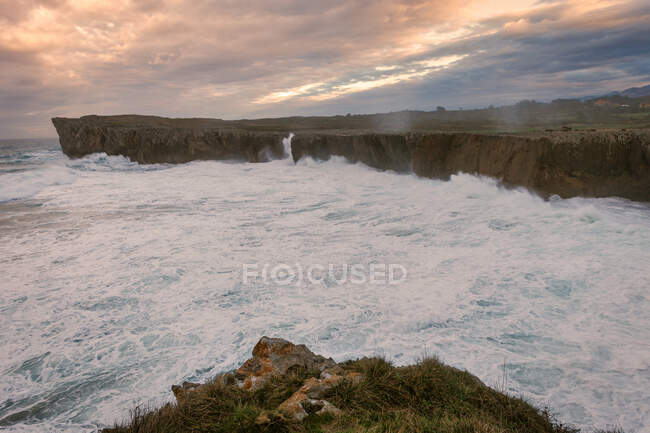 Мощная волна плескается на гранитной скале — стоковое фото