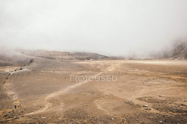 Rocky terrain with clouds of mist over mountains in Tongariro in New Zealand — Stock Photo