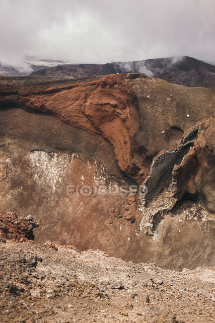 Rocky terrain with clouds of mist over mountains in Tongariro in New Zealand — Stock Photo