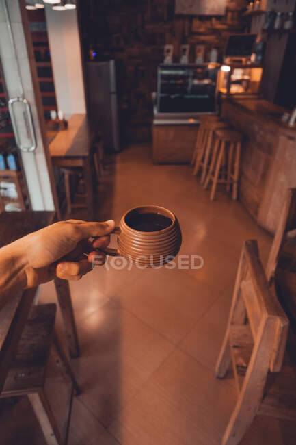 Erntehelfer hält Tasse Kaffee auf Tisch — Stockfoto