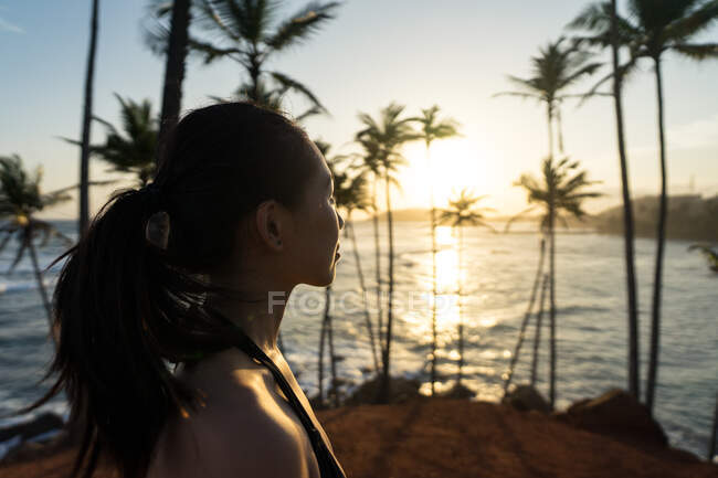 Tranquillo viaggiatore femminile tra le palme in riva al mare — Foto stock