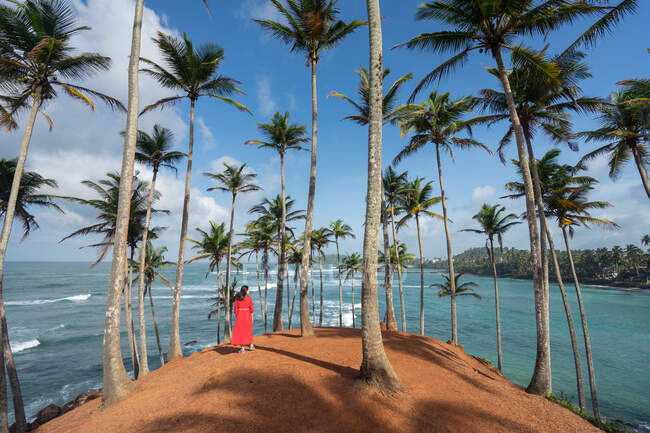 Tranquilo viajante feminino entre as palmas das mãos na praia — Fotografia de Stock