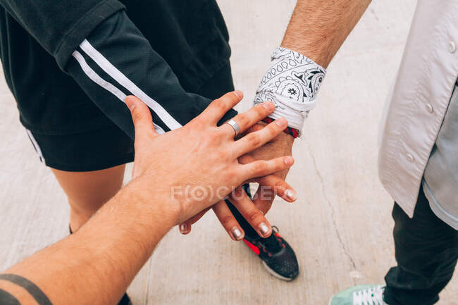 From above of crop stacking hands of faceless friends in casual wear standing on ground — Stock Photo