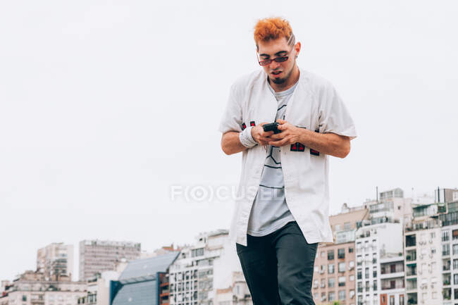 Contemporary male teenager in casual trendy browsing phone — Stock Photo