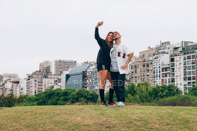 Friends smiling while making selfie on smartphone at city — Stock Photo