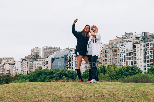 Amigos sorrindo enquanto fazem selfie no smartphone na cidade — Fotografia de Stock