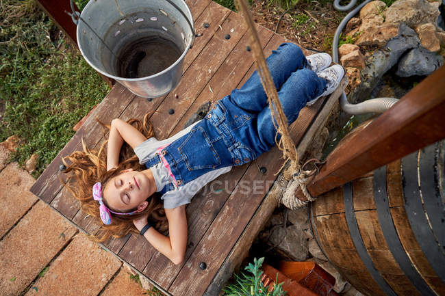 Sonriendo inocente chica acostada en casa patio trasero - foto de stock
