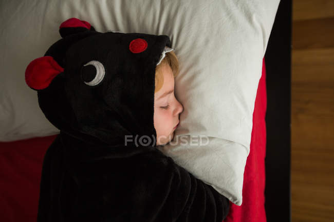 Little boy in black kigurumi pajama sleeping in bed — Stock Photo