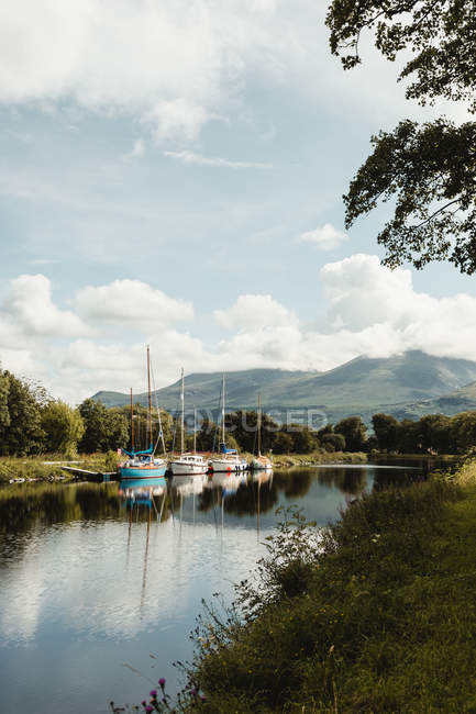 Amazing picturesque landscape of river with colorful moored vessels at pier under blue sky with white clouds in Scotland — Stock Photo