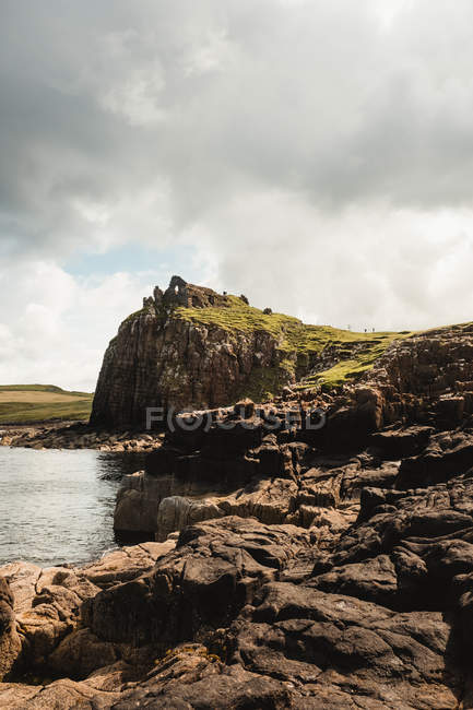 Costa rochosa entre a água tranquila do oceano durante o dia ensolarado na Escócia — Fotografia de Stock