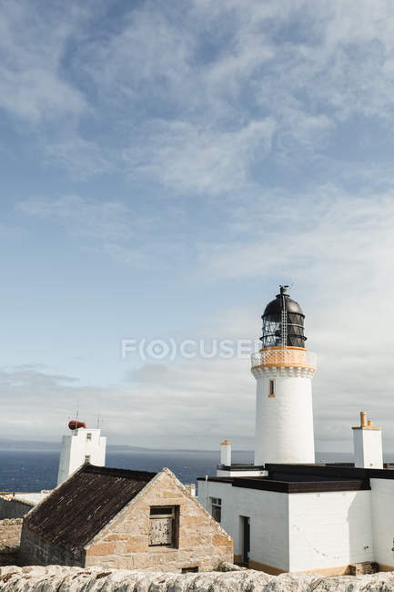 Hermoso faro Dunnet Head blanco en las tierras altas escocesas con cielo azul y nubes blancas - foto de stock