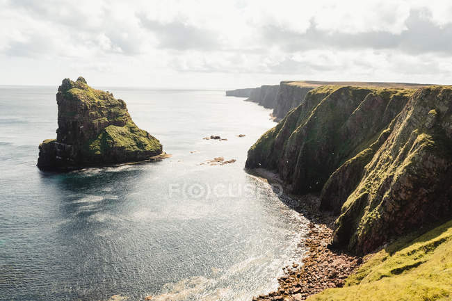 Felsige Küste inmitten ruhigen Ozeanwassers an sonnigen Tagen in Schottland — Stockfoto