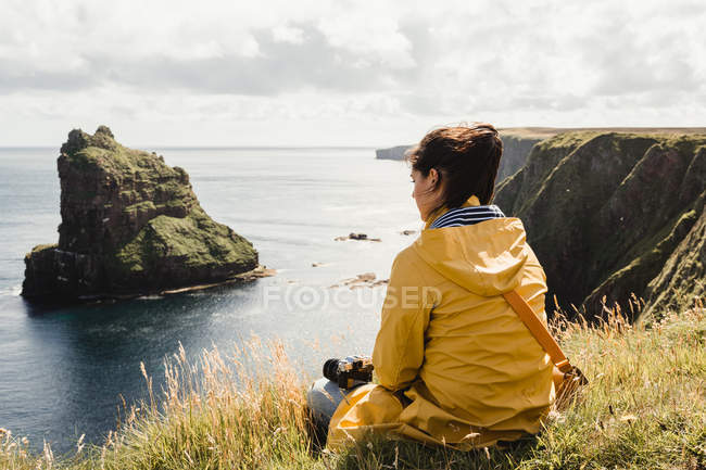 Sereno turista disfrutando de la vista del tranquilo valle verde en un clima nublado en Escocia - foto de stock