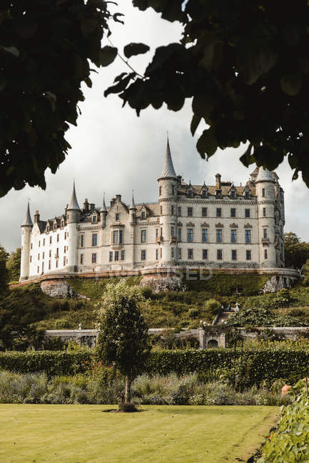 Paesaggio panoramico del bellissimo castello medievale scozzese con giardino su verdi colline contro il cielo nuvoloso in Scozia — Foto stock