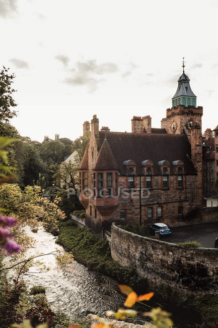 Paysage étonnant avec château médiéval le long de la petite rivière et de la forêt dans le vieux village écossais — Photo de stock