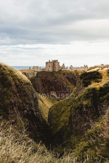 Paesaggio paesaggistico di verdi colline con vecchi edifici in pietra in lontananza e cielo grigio nuvoloso negli altopiani scozzesi — Foto stock