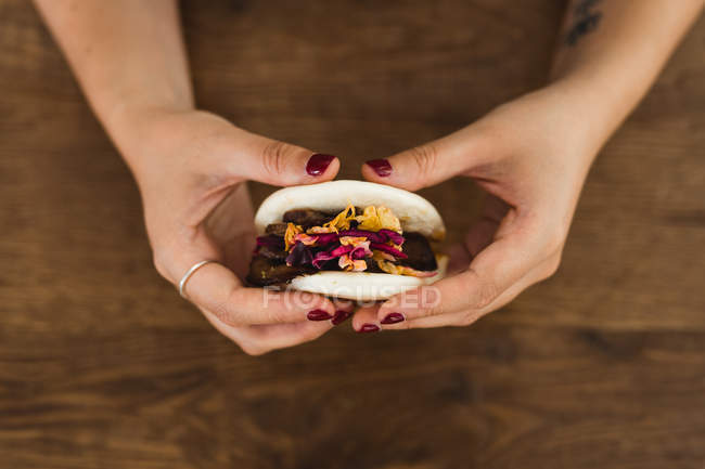 From above of hands of woman holding traditional Asian steamed bun sandwich with meat and vegetables — Stock Photo