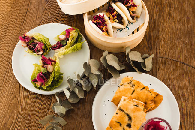 Varia selezione di diversi piatti asiatici su piatti disposti in tavolo di legno — Foto stock
