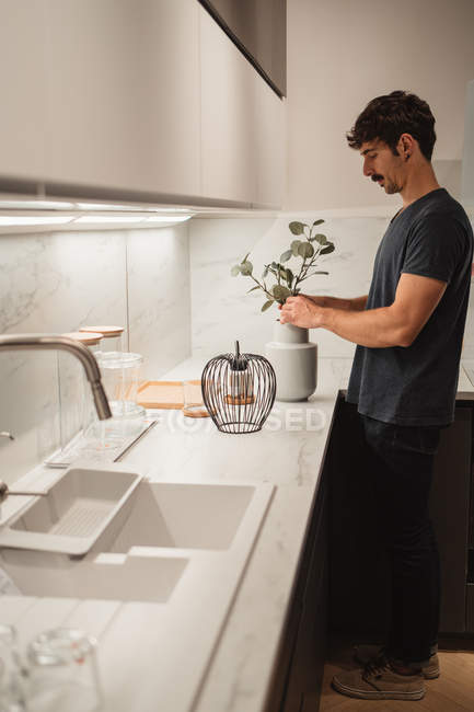 Uomo mettendo fiori in vaso sulla cucina moderna — Foto stock