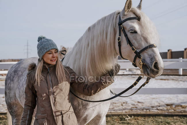 Donna vestita di caldo con cavallo grigio all'esterno — Foto stock