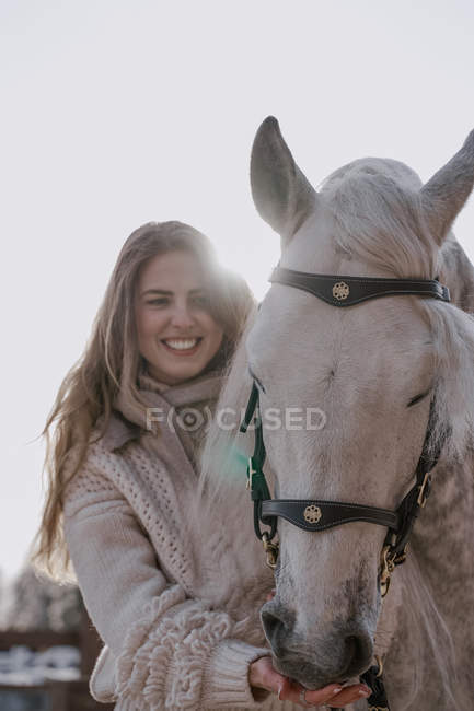Femme chaude habillée avec cheval gris dehors dans la cour de la ferme — Photo de stock
