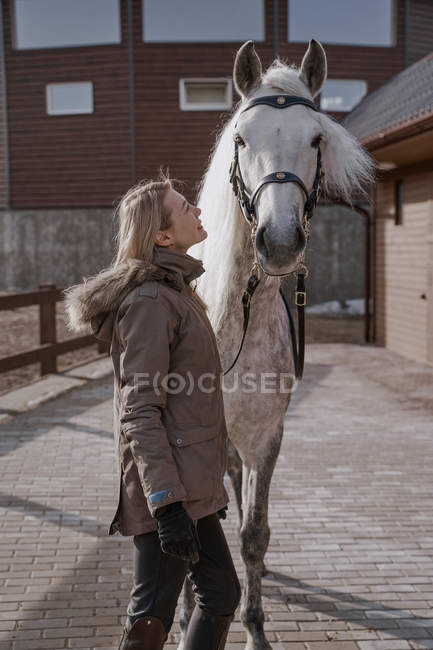 Warm gekleidete Frau mit grauem Pferd draußen auf Bauernhof — Stockfoto