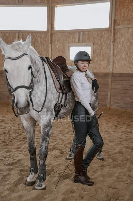 Horsewoman standing with dapple gray horse in round arena — Stock Photo