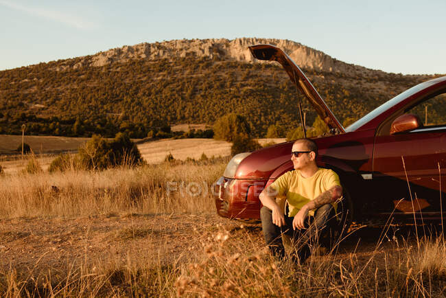 Man leaning in broken car in countryside — Stock Photo