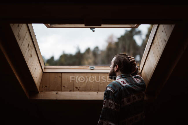 Мужчина в отпуске наслаждается из окна дома — стоковое фото
