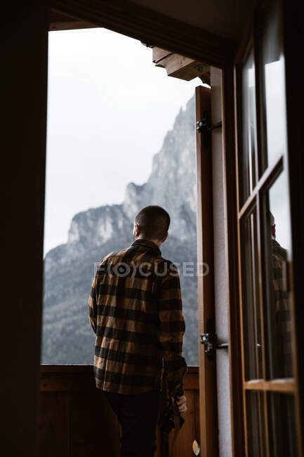 Чоловік у повсякденному одязі стоїть біля вікна — стокове фото