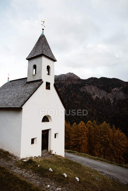 Маленькая церковь на скале возле леса и гор — стоковое фото