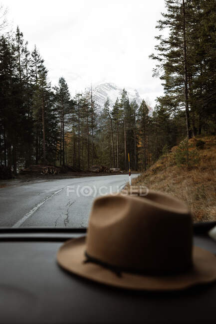Chapéu dentro de um carro na estrada solitária em meio a montanhas — Fotografia de Stock