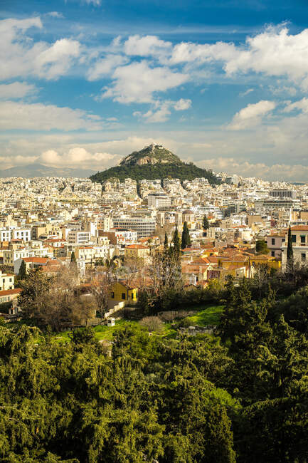 Immeubles situés près du sommet verdoyant de la montagne par temps nuageux à Athènes, Grèce — Photo de stock