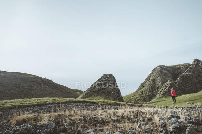 Mulher anônima desfrutando paisagem cênica incrível da Irlanda do Norte durante a viagem enquanto caminhava em solo rochoso — Fotografia de Stock