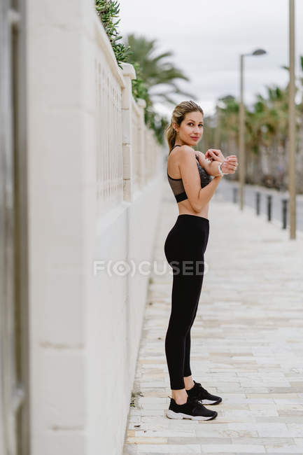 Athlete woman in active wear standing near seashore on cloudy weather — Stock Photo