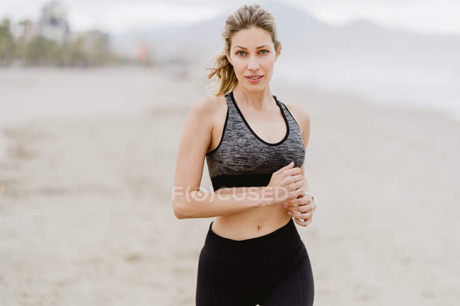 Fit woman running along tropical empty seashore on cloudy weather — Stock Photo