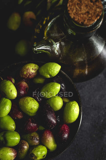 Huile d'olive extra vierge espagnole fraîche avec olives et vieille branche d'olive sur fond sombre Alimentation saine Régime méditerranéen. Végétalien. Végétarien — Photo de stock