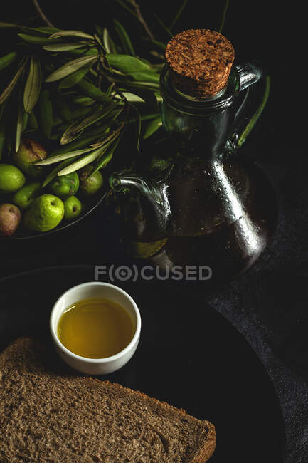 Frisches spanisches natives Olivenöl extra mit Oliven und altem Olivenzweig auf dunklem Hintergrund Gesunde Ernährung mediterrane Ernährung. Veganer. Vegetarier — Stockfoto