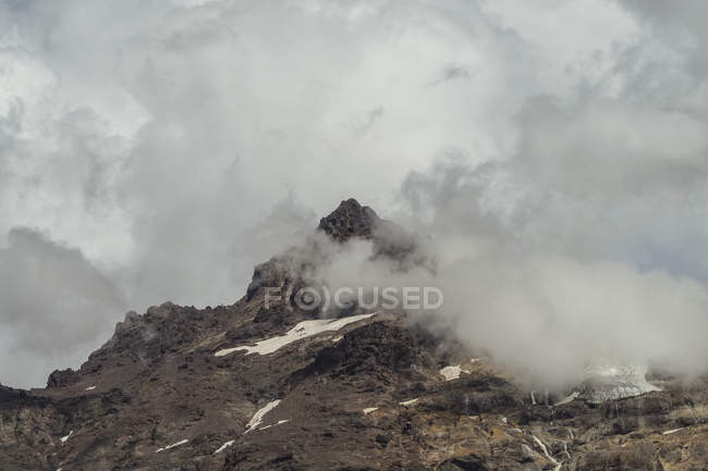 Grandi rocce rocciose ricoperte di neve nella misteriosa foschia del Parco Nazionale Laguna del Laja, Cile — Foto stock