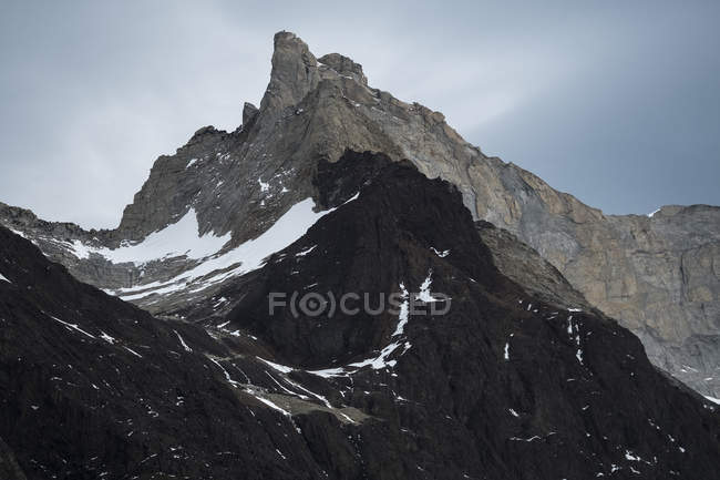 Gloomy lonely mountain peak under cloudy sky in rocky valley in Torres del Paine National Park, Chile — Stock Photo